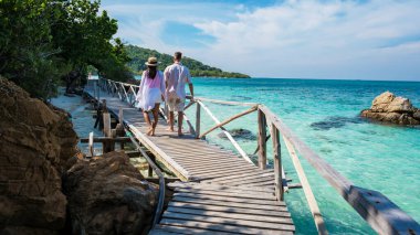 A couple of man and woman on a boat trip at Ko Kham Island Sattahip Chonburi Samaesan Thailand, a couple at a wooden bridge jetty on a tropical island with turqouse colored ocen clipart