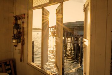 Samaesan Tayland 'ın balıkçı kasabasının okyanus kıyısındaki bir köyünde gün batımında ahşap bir pencereden bakmak.