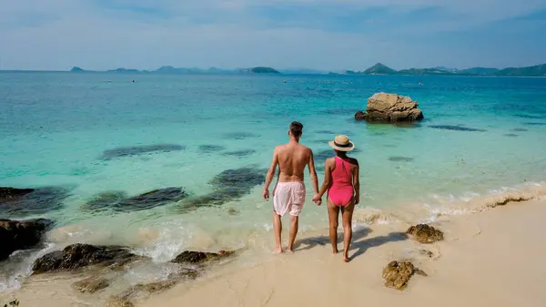 A couple of European men and Asian woman on a boat trip at Ko Kham Island Sattahip Chonburi Samaesan Thailand, a couple walking in the ocean at a tropical island with turqouse colored ocen