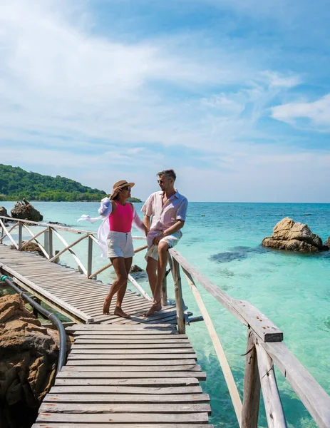 A couple of European men and an Asian woman on a boat trip at Ko Kham Island Sattahip Chonburi Samaesan Thailand, a couple at a wooden bridge jetty on a tropical island with turqouse colored ocen