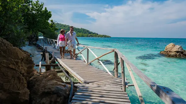 A couple of European men and an Asian woman on a boat trip at Ko Kham Island Sattahip Chonburi Samaesan Thailand, a couple at a wooden jetty on a tropical island with turqouse colored ocen