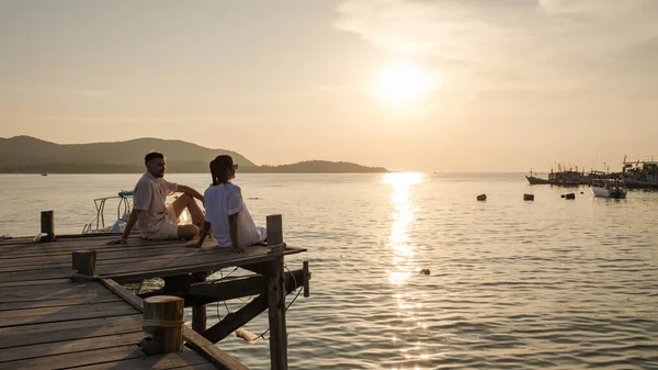 一对欧洲男人和一个亚洲女人正在泰国度假 一对夫妇正在观看日落时在泰国沙马的一个木制甲板码头上的落日 — 图库照片