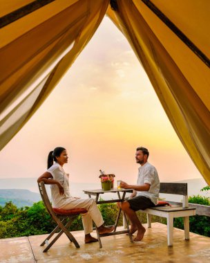 Phitsanulok Tayland 'daki bir dağ kampında gün batımını izleyen bir çift kadın ve erkek. Kuzey Tayland 'da lüks içinde yaşamak, doğada bir çadırda kamp yapmak.