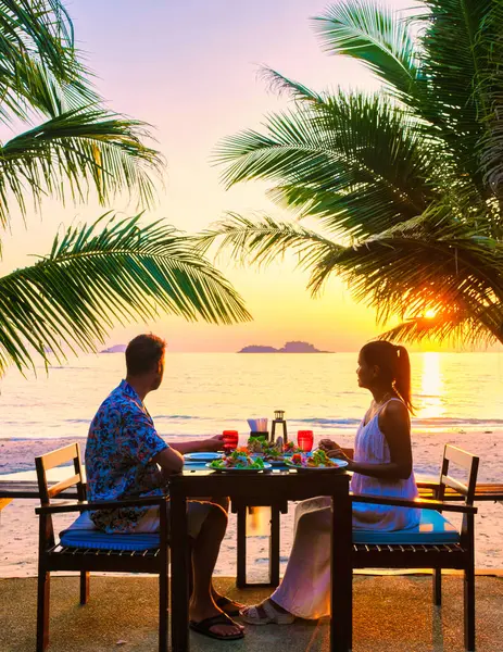 ハネムーンの休暇中に高級リゾートでパームツリーとビーチで夕日 男性と女性の夕食の間にコチャンタイのビーチでロマンチックなディナーを持っているカップル — ストック写真