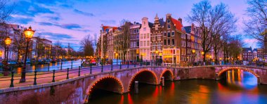 Akşam saatlerinde Amsterdam Kanalı, Amsterdam Kanalı köprüsü ve Hollanda 'da eski tarihi evler.
