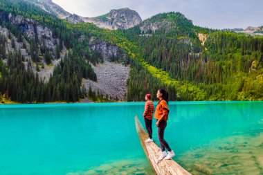 Joffre Lakes, Kanada 'daki Joffre Lakes Ulusal Parkı' nın renkli bir gölü olan British Colombia Whistler Canada 'da göldür. Bir çift Asyalı kadın ve Kafkasyalı erkek BC Jofre Gölü 'nde yürüyorlar.
