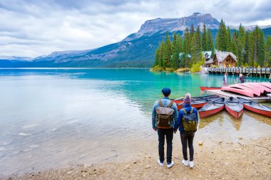Emerald Lake Yoho Ulusal Parkı Kanada İngiliz Kolombiyası. Sonbahar sezonunda Kanada Kayalıkları 'nda güzel bir göl. Bir çift kadın ve erkek gölün kenarında durup dağlara bakıyorlar.