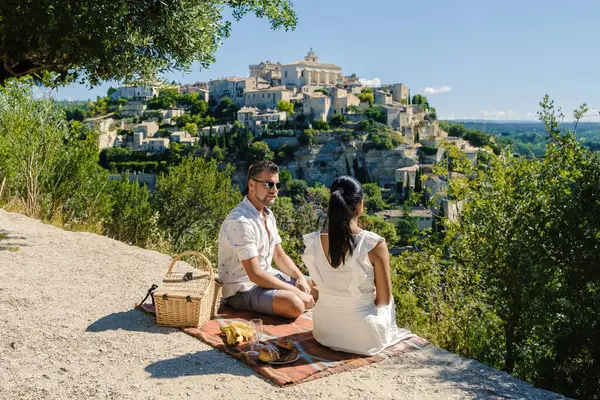 A couple of men and women on vacation in Southern France, looking out over the old historical village of Gordes Luberon Provence during summer in Europe