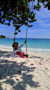 Tayland 'da güneşli bir günde, Koh Samed Tayland' da, Koh Samet Adası 'nda salıncakta sallanan Asyalı Taylandlı kadınlar.