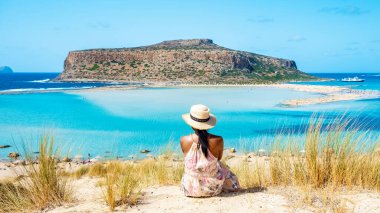 Girit Adası Yunanistan 'da Girit Yunanistan Balos gölü. Turistler, Balos Sahili Girit 'in berrak okyanusunda dinleniyorlar ve Yunanistan' da tatil yapan Asyalı bir kadın plajı ziyaret ediyor