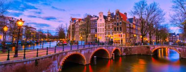 Akşam saatlerinde Amsterdam Kanalı, Amsterdam Kanalı köprüsü ve Hollanda 'da eski tarihi evler.