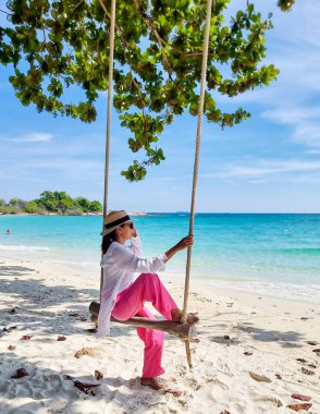 Samed Adası 'nın beyaz tropikal plajı olan Koh Samet Adası Rayong Tayland sahilinde salıncakta sallanan Asyalı bir kadın güneşli bir öğleden sonra turkuaz renkli bir okyanusa sahip.