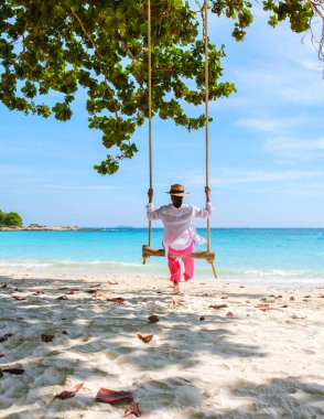 Samed Adası 'nın beyaz tropikal plajı Koh Samet Adası Rayong Tayland' da salıncakta sallanan Asyalı bir kadın. Turkuaz renkli bir okyanusu var.