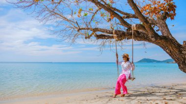 Samed Adası 'nın beyaz tropikal plajı Koh Samet Adası Rayong Tayland' da salıncakta sallanan Asyalı bir kadın. Turkuaz renkli bir okyanusu var.