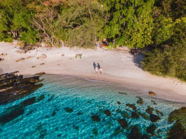 Koh Samet Adası Tayland, Tayland 'da gün doğumunda Samed Adası sahilinde birkaç erkek ve kadının üzerinde havadan insansız hava aracı görüntüsü. Turkuaz renkli bir okyanus ve beyaz tropikal bir plaj.