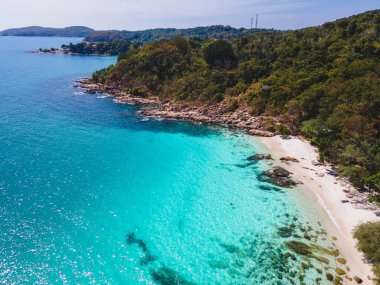 Koh Samet Adası Tayland 'ın yukarısından tropikal bir körfez. Tayland' ın Samed Adası 'ndan havadan insansız hava aracı görüntüsü. Üzerinde turkuaz renkli bir okyanus ve İHA manzaralı beyaz bir tropikal plaj var.