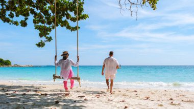 Birkaç erkek ve kadın, Koh Samet Adası Tayland sahilinde salıncakta sallanıyor. Samed Adası 'nda turkuaz renkli bir okyanusu olan tropik bir plaj. Asyalı kadınlar ve Avrupalı erkekler Tayland 'da tatildeler