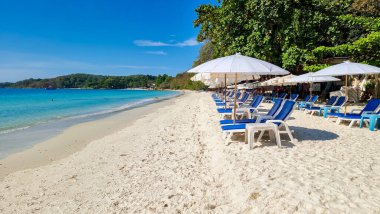 Samed Adası 'nın beyaz tropikal sahilinde şemsiyelerle güneşlenmiş plaj sandalyeleri Koh Samt Adası Tayland' ın turkuaz renkli okyanusu ile