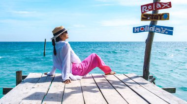 Koh Samet Adası 'ndaki tahta iskelede Asya' lı bir kadın. Rayong Tayland, Samed Adası 'nın beyaz tropik plajı. Turkuaz renkli bir okyanusu var.