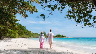 Samed Adası 'nın beyaz tropikal plajı olan Koh Samet Adası Rayong Tayland sahilinde turkuaz renkli bir okyanusu olan bir çift erkek ve kadın yürüyordu.