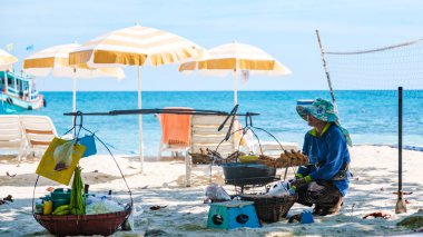 Koh Samet Adası Rayong Tayland 10 Aralık 2023, Samed Adası 'nda turkuaz renkli bir okyanusu olan tropik bir sahilde yiyecek satan bir plaj satıcısı.