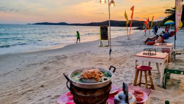 Koh Samet Adası Rayong Tayland 10 Aralık 2023, günbatımında Samed Adası 'nda turkuaz renkli bir okyanusu olan tropikal bir sahil. Gün batımında sahilde bir restoranda plaj sandalyeleri.