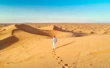 Dubai çöl kum tepeleri, Dubai çöl safarisindeki erkekler, Birleşik Arap Emirlikleri tatili, Dubai Emirlikleri 'nde kum tepelerinde yürüyen adamlar.