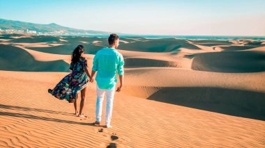 Maspalomas Gran Canaria İspanya sahillerinde yürüyen çift, Maspalomas İspanya 'nın kumul çöllerinde sabah güneşinde Avrupa' nın erkek ve kadın