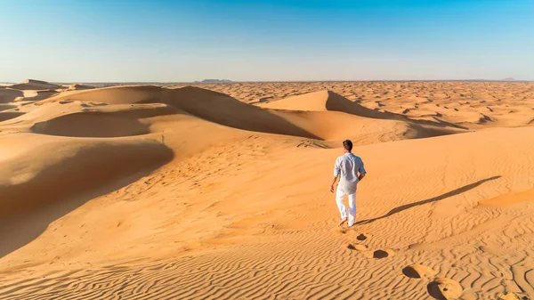 Dubai desert sand dunes, men on Dubai desert safari, United Arab Emirates vacation, men on vacation in Dubai Emirates walking in the sand dunes during vacation in Dubai