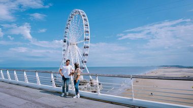 Dönme dolap Scheveningen Rıhtımı. Hollanda Lahey 'de bir bahar günü, güneşli bir günde bir adam ve bir kadın rıhtımda dikiliyor.