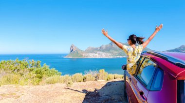 Araba penceresinin dışında elleri havada bir kadın, Chapman 's Peak Drive' da bir araba Cape Town Güney Afrika 'da okyanusa bakıyor. Güney Afrika 'daki bahçe yolunda, renal bir arabayla yolculuk yapan kadınlar.