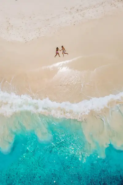 熱帯のビーチに横たわる男性と女性 セイシェルコス島の熱帯ビーチで上からドローンビュー トロピカルビーチで上から眺める 休暇中のカップル — ストック写真