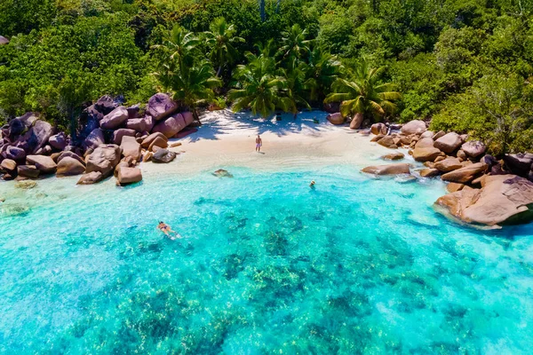 Anse Lazio Plajı Praslin Seyşeller Tropikal adası, beyaz plajları ve palmiye ağaçları, Seyşeller 'de tatilde olan birkaç erkek ve kadın.