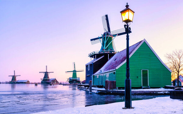snow covered windmill village in the Zaanse Schans Netherlands, historical wooden windmills in winter Zaanse Schans Holland during winter weather at sunrise with snow