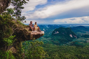 Ejderha Tepesi dağı Krabi Tayland, genç bir gezgin uçurumun üzerindeki kayanın üzerinde oturuyor, güzel bir manzarası var. Tayland, Krabi 'deki Khao Ngon Nak Doğa Yolu' nda Ejder Tepesi veya Khuan Sai.