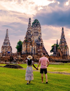 Şapkalı erkekler ve kadınlar Ayutthaya Thailand 'ı gün batımında Wat Chaiwatthanaram' da ziyaret ediyorlar.