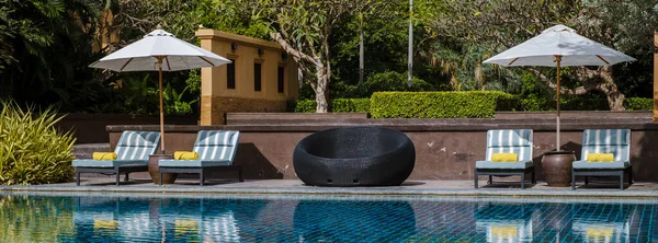 在一家豪华酒店游泳池边的雨伞和豪华海滩椅 — 图库照片