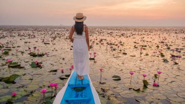 Kızıl Lotus Denizi, Nong Harn Gölü, Udon Thani, Tayland. Isaan 'daki kırmızı Lotus Gölü' nde bir teknede şapka ve elbisesi olan Asyalı kadın.