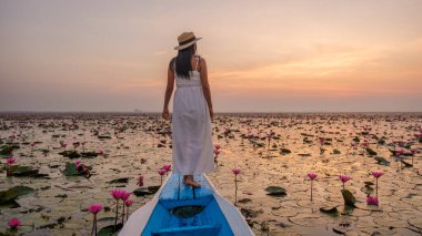 Kızıl Lotus Denizi, Nong Harn Gölü, Udon Thani, Tayland. Isaan 'daki Red Lotus Gölü' nde bir teknede şapkası ve elbisesi olan Asyalı kadın.