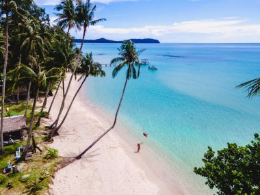 Tropik Koh Kood Adası veya Koh Kut Tayland. Tayland 'da tatilde olan birkaç erkek ve kadın sahilde yürüyor, Tatil konsepti adası Doğu Tayland Trang' da zıplıyor, ip salıncaklı bir çift