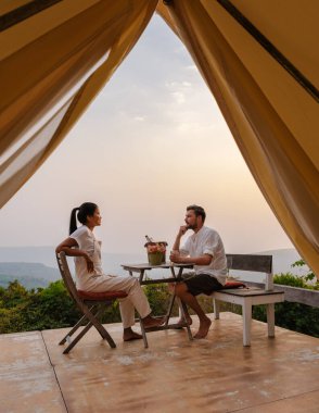 Phitsanulok Tayland 'daki bir dağ kampında gün batımını izleyen bir çift kadın ve erkek. Dağlarda lüks içinde, doğa.