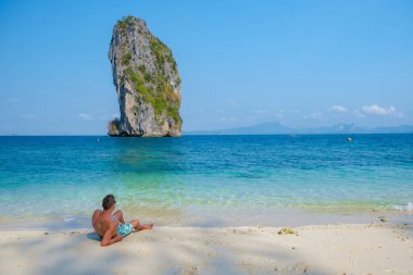 Koh Poda Plajı 'ndaki genç adamlar Krabi Tayland, Koh Poda Adası' nın tropikal plajı Yengeç adam, sahilde kısa süre uzandı., 