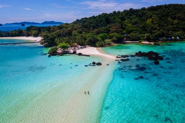 Koh Kham Trat Tayland sahilinde yürüyen çift, Koh Mak Tayland yakınlarındaki tropik adanın insansız hava aracı görüntüsü. Beyaz kumlu sahil, palmiye ağaçları ve okyanusta büyük siyah kaya taşları.
