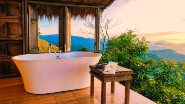 Tatil sırasında Chiang Rai Kuzey Tayland dağlarına bakan küvet. Dışarıda banyo, gün batımında küvet.