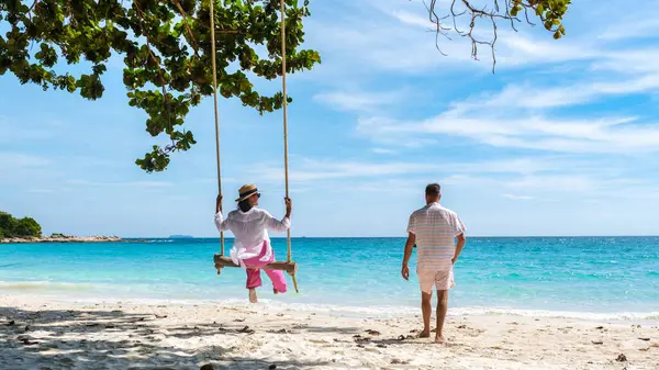 Birkaç erkek ve kadın, Koh Samet Adası Rayong Tayland sahilinde salıncakta sallanıyor. Samed Adası 'nın beyaz tropikal plajı. Turkuaz renkli bir okyanusu var..