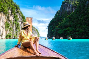 Kho Phi Tayland 'da uzun kuyruklu bir teknenin önündeki Asyalı kadınlar, Maya Körfezi Koh Phi Phi gezisi sırasında turkuaz renkli okyanusları olan Pileh lagünündeki bir teknenin önündeki kadınlar. 