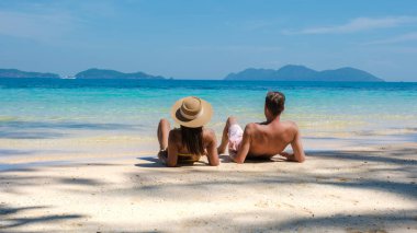 Koh Wai Adası Trat Tayland, Koh Chang yakınlarında teneke bir tropikal adadır. Tayland 'da lüks bir tatil sırasında tropikal sahilde bir çift genç erkek ve kadın, kumsalda uzanan bir çift.
