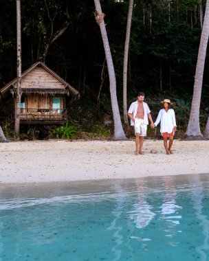 Koh Wai Adası Trat Tayland, Koh Chang yakınlarında teneke bir tropikal adadır. Kumsaldaki ahşap bambu kulübesi. Tayland 'da tropik bir adada genç bir çift kadın ve erkek.