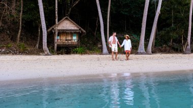Koh Wai Adası Trat Tayland, Koh Chang yakınlarında teneke bir tropikal adadır. Kumsaldaki ahşap bambu kulübesi. Genç bir çift gün batımında Tayland 'da tropikal bir adada.