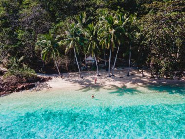 Koh Wai Adası Trat Tayland Koh Chang yakınlarında teneke bir tropik ada. Plajda palmiye ağaçlarıyla kaplı ahşap bambu kulübesi. Tayland 'da tropik bir adada genç bir çift kadın ve erkek.